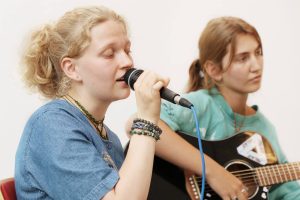 Zwei Schülerinnen begleiten die Vernissage musikalisch mit Gesang und Gitarre.