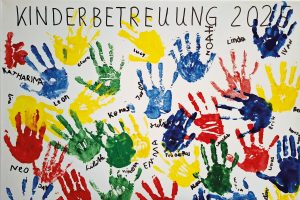 Plakat mit der Überschrift Kinderbetreuung 2025 und vielen Handabdrücken, die mit Namen beschriftet sind.