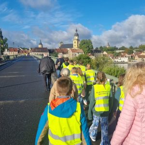 Kinder laufen über die Alte Mainbrücke von Kitzingen in Richtung Innenstadt. Der Turm der evangelischen Kirche ist zu sehen.