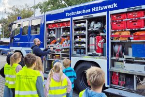 Ein Mitarbeiter des THW Kitzingen präsentiert einigen Kindern das Einsatzfahrzeug.