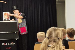 Zauberer Mäd Schick führt den Kindern Zaubertricks vor.