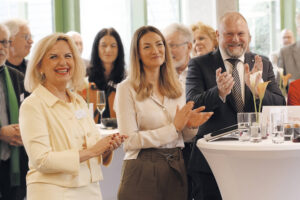 Landrätin Tamara Bischof, Staatsministerin Gerlach und Landrath Thomas Eberth klatschen Beifall. Im Hintergrund sind andere Veranstaltungsgäste zu sehen.