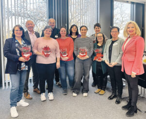 Praxisanleiterinnen mit Blumen in den Händen, Der Vorstand der Klinik Kitzinger Land, die Pflegeleitung Birgit Jakob und die Landrätin Tamara Bischof blicken lächelnd in die Kamera.